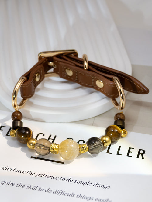 SoulBond Crystal Beaded Pet Collar displayed on a printed page with the brown strap resting against a white ridged stand