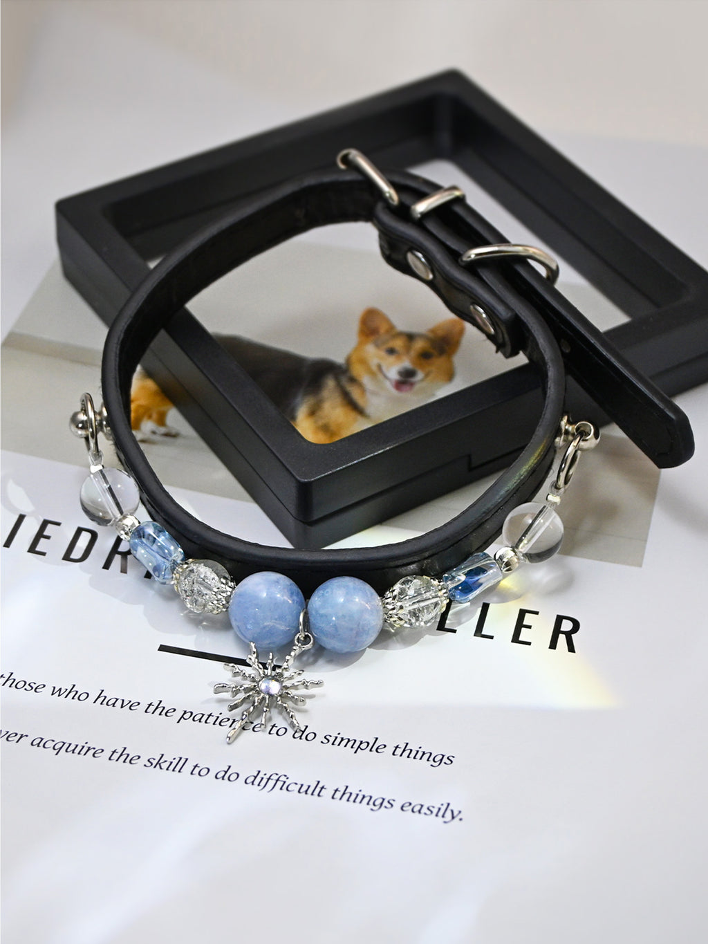 SoulBond Elegant Princess Crystal Pet Collar with blue beads arranged over a black frame and a printed page