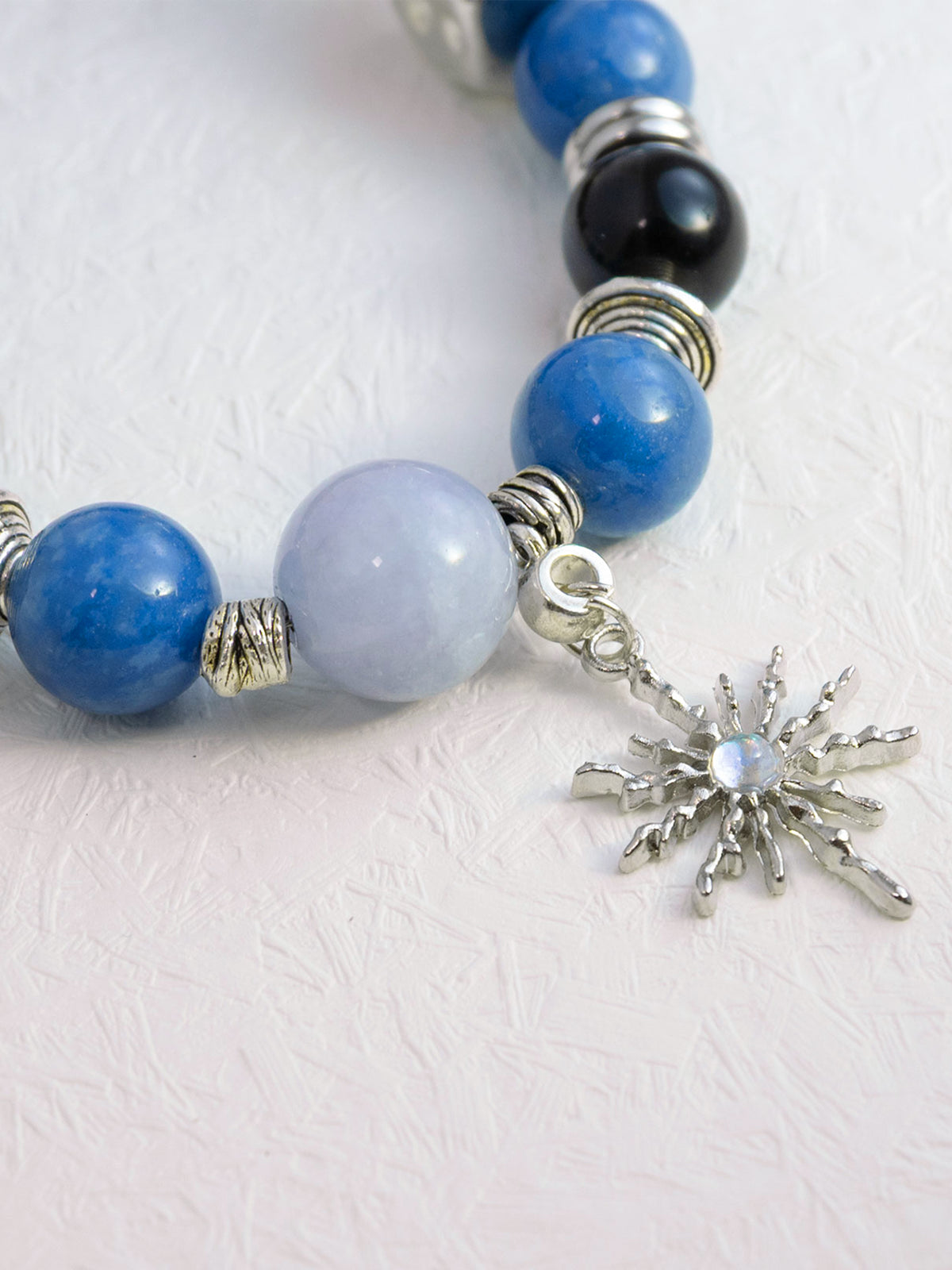 SoulBond Sweet Crystal Cat Collar detail showing a pale blue center bead and silver-tone starburst charm on white fabric