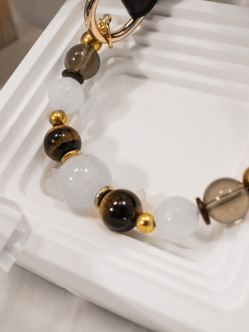 SoulBond Old Money Crystal Beaded Cat Collar showing white, smoky brown and striped beads on a white ridged tray