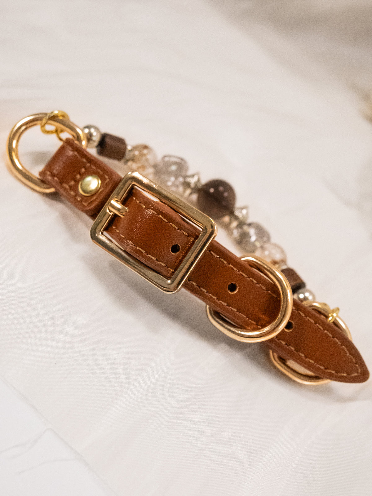 SoulBond Vintage Crystal Cat Collar detail showing a gold-tone buckle, adjustment holes and stitching on the brown strap