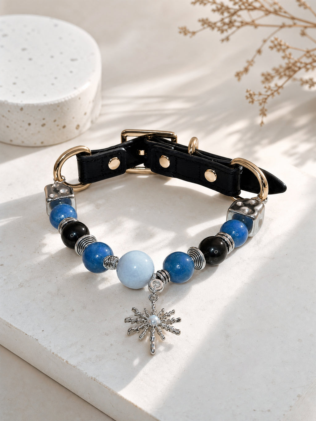SoulBond Sweet Crystal Cat Collar with blue and black beads displayed in sunlight beside dried stems