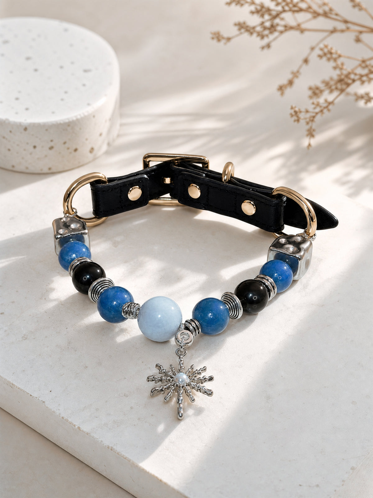 SoulBond Sweet Crystal Cat Collar with blue and black beads displayed in sunlight beside dried stems