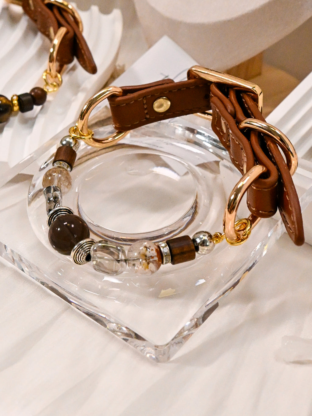 SoulBond Vintage Crystal Cat Collar displayed on a clear square dish with its brown strap and gold-tone rings visible