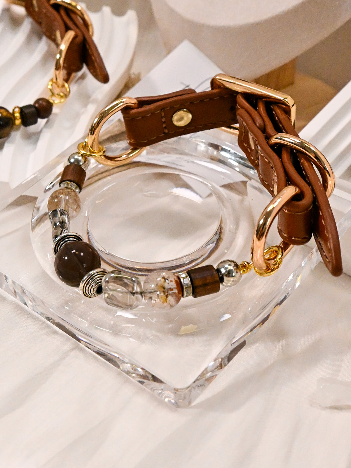 SoulBond Vintage Crystal Cat Collar displayed on a clear square dish with its brown strap and gold-tone rings visible