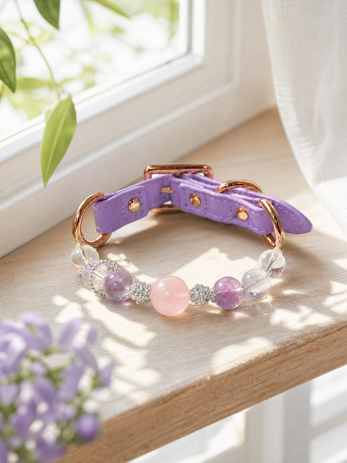SoulBond Princess Crystal Cat Collar on a sunlit wooden windowsill beside green leaves and purple flowers