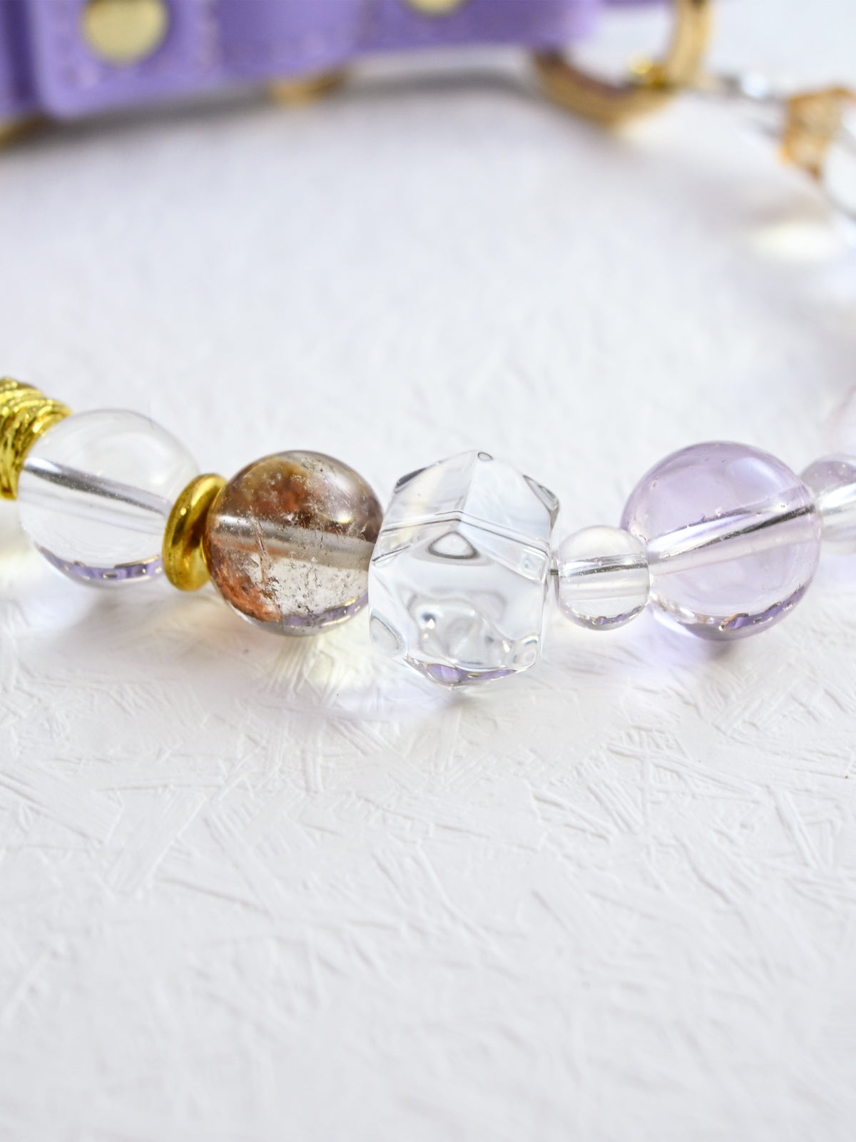 SoulBond White Crystal Cat Collar close-up of a clear angular bead beside pale purple and brown-speckled round beads