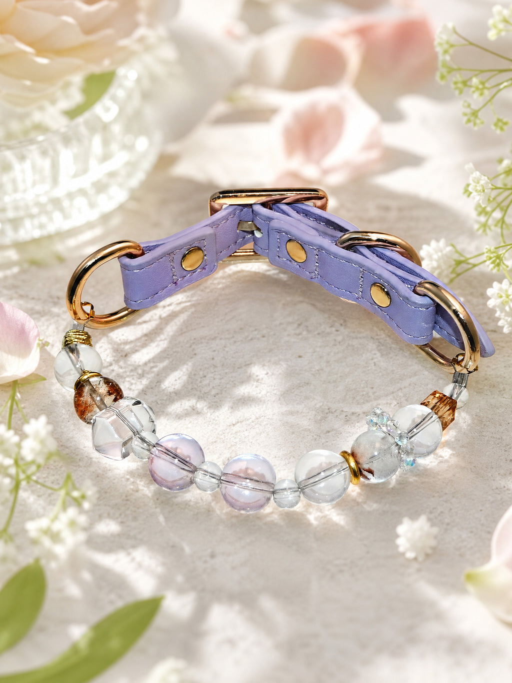 SoulBond White Crystal Cat Collar on a pale textured surface surrounded by pink petals and small white flowers