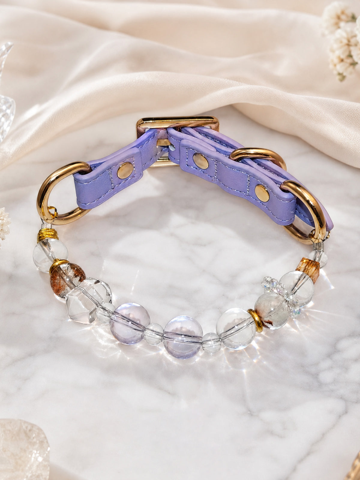 SoulBond White Crystal Cat Collar with clear and pale purple beads on a white veined surface beside cream fabric